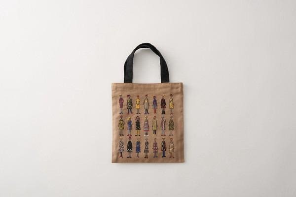 A beige tote bag with a black handle, featuring a repeating pattern of colorful illustrations of people in various outfits.