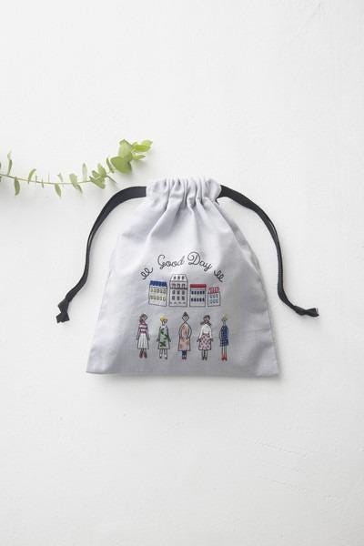 A white drawstring bag with a printed design of five stylized figures in various outfits, along with the text "Good Day" printed on it.