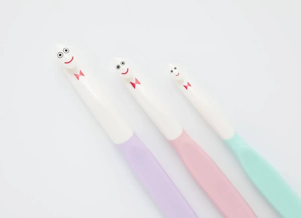 Three toothbrushes with smiling faces are arranged in a row against a white background.