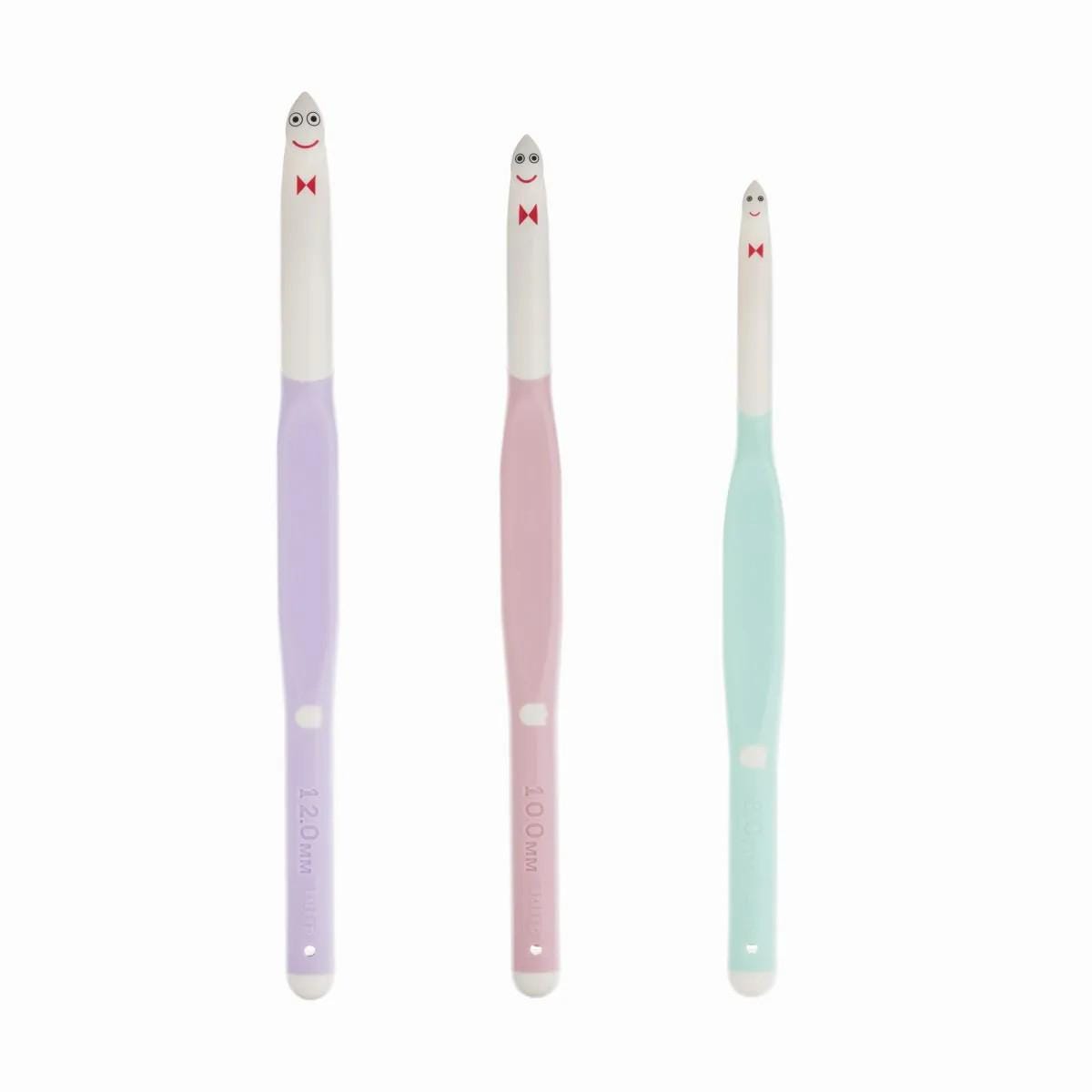 three crochet hooks with smiling faces on their tips.
