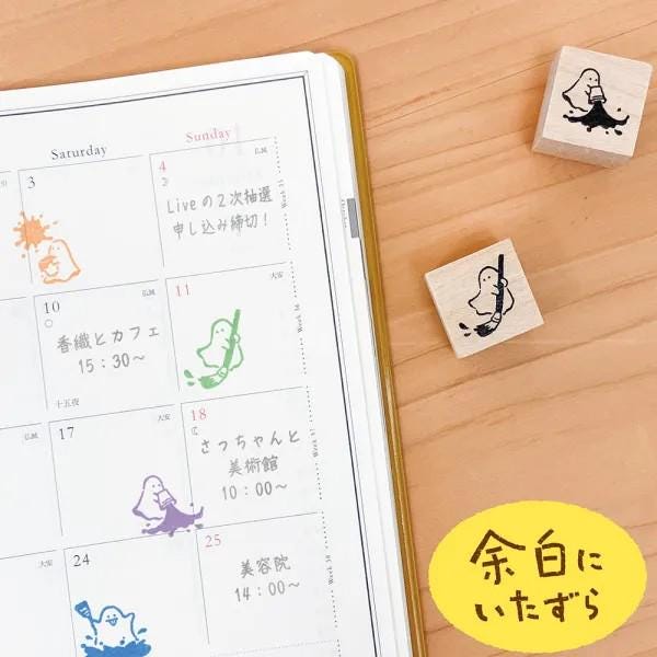 a calendar with various colored stickers and a yellow sticker with Japanese text on a wooden surface.
