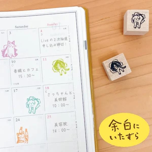 a calendar with a variety of colorful animal stamps placed on top of it, along with a yellow sticker with Japanese text.