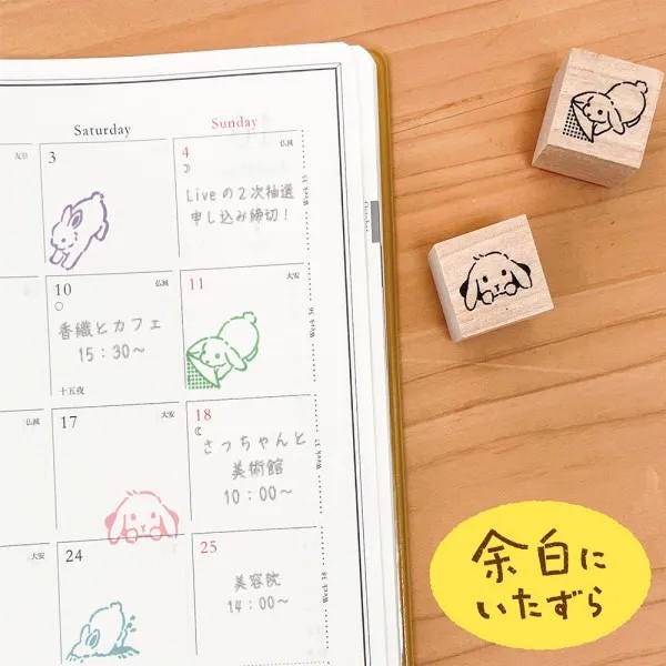 a calendar with a cute rabbit stamp on it, along with three wooden stamps shaped like rabbits. The calendar is open and placed on a wooden surface, with the rabbit stamps and wooden stamps arranged next to it.