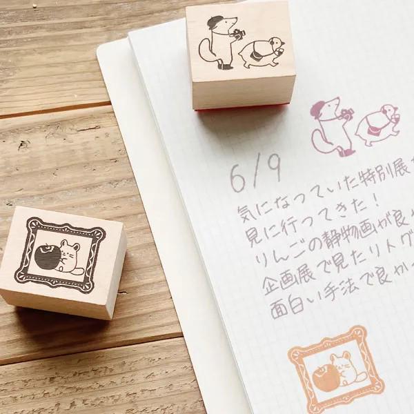 a collection of three wooden stamps and a piece of paper with Japanese text on it, all placed on a wooden surface.