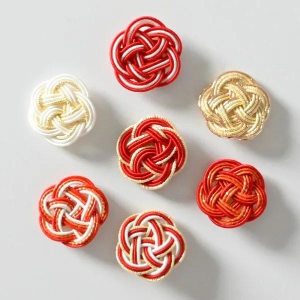 a collection of six intricately woven objects, each with a unique knot pattern and color scheme. The objects are arranged in a circular pattern, showcasing the craftsmanship and artistry involved in their creation.