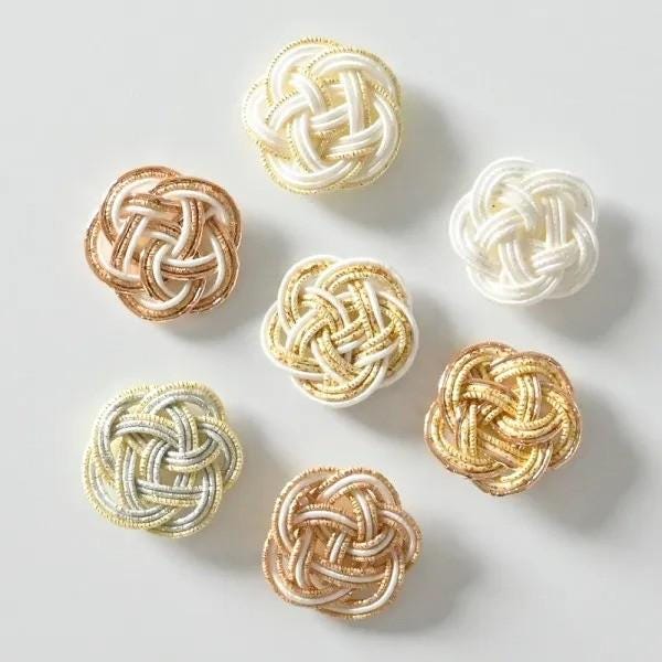 a collection of six knotted objects in various colors, including gold, white, and silver, arranged in a circular pattern.