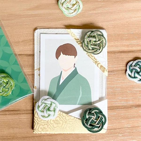a framed illustration of a person wearing a green kimono, surrounded by green and white knotted ornaments.