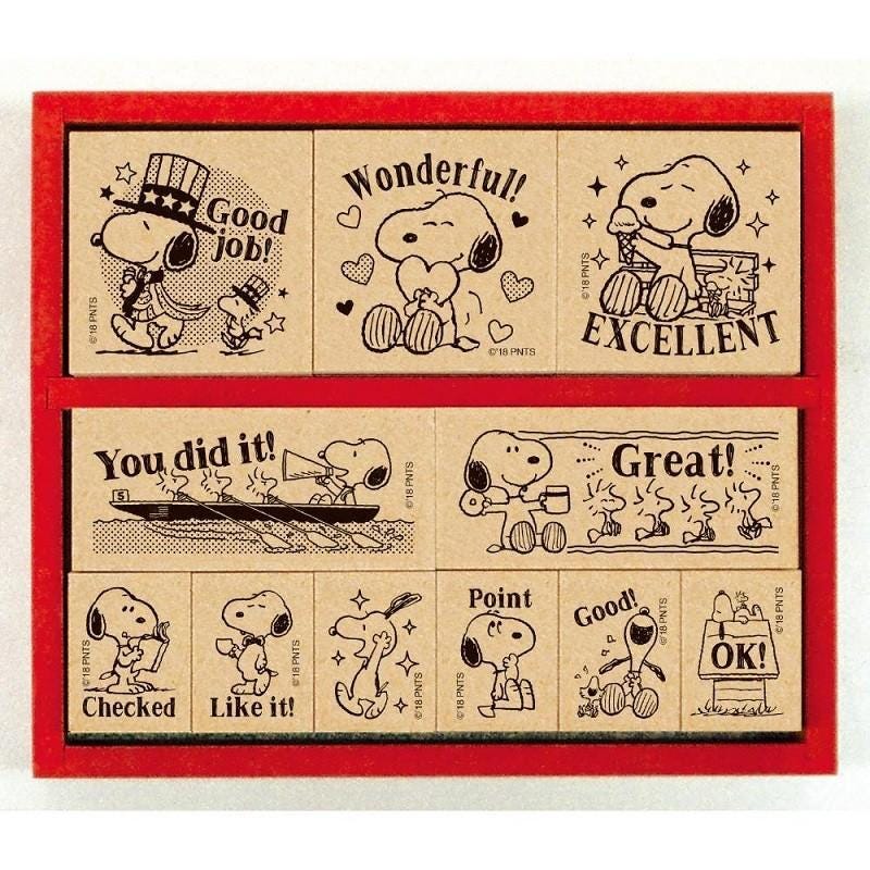 a collection of cartoon-style stamps or postcards featuring characters from the Peanuts comic strip. The stamps display various expressions and actions, such as "Good job!", "Wonderful!", "Excellent", "You did it!", "Point", "Good!", and "OK!". The stamps are arranged in a grid-like pattern within a red frame, showcasing the diverse range of emotions and actions depicted by the characters.