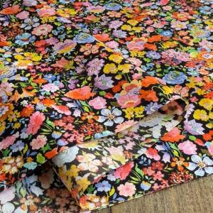 a vibrant, colorful fabric with a floral pattern. The fabric appears to be a mix of various flowers in different colors, creating a visually striking and lively design.