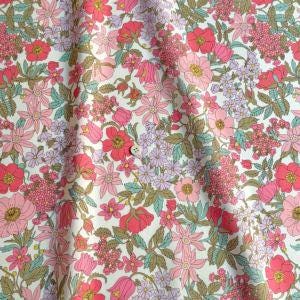 a close-up view of a fabric with a vibrant floral pattern. The fabric is predominantly white, adorned with a variety of colorful flowers in shades of pink, red, and purple. The flowers are arranged in a repeating pattern, creating a visually striking and intricate design. The fabric appears to be made of a soft, plush material, suitable for clothing or home decor.