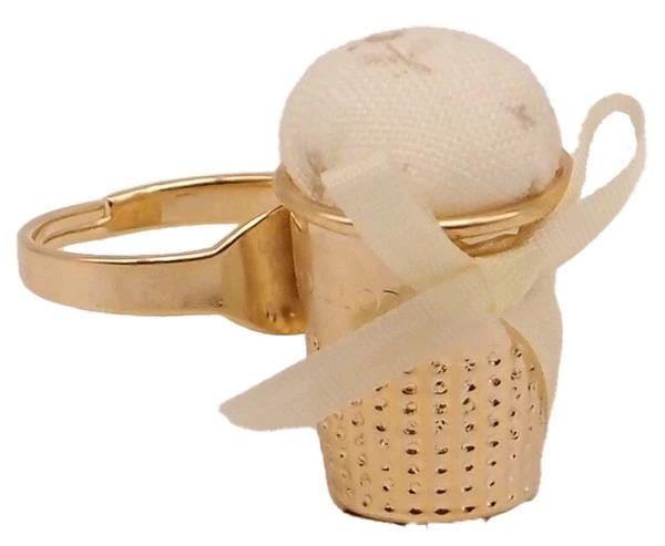A gold-colored ring with a small white ball or object placed inside it, tied with a white ribbon.