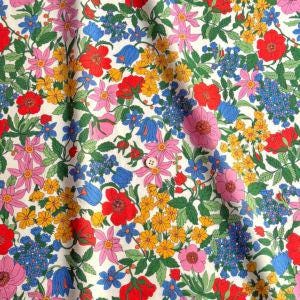 The image is a vibrant and colorful fabric with a repeating pattern of various flowers and leaves in different colors, including red, pink, yellow, blue, and green.