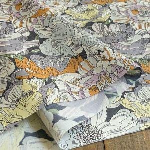 a close-up view of a fabric with a floral pattern, including various shades of purple, orange, and white flowers.