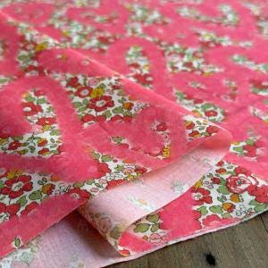 a close-up view of a fabric with a floral pattern in shades of pink and white.
