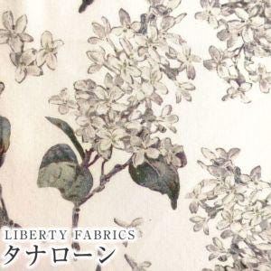 The image is a close-up of a fabric with a floral pattern, featuring white flowers and green leaves. The fabric appears to be a type of cotton or linen material, with the text "LIBERTY FABRICS" visible.
