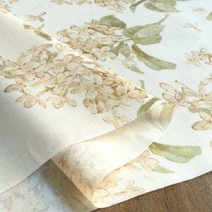 a close-up view of a fabric with a floral pattern, including white flowers and green leaves. The fabric appears to be folded or rolled, with the edges visible.