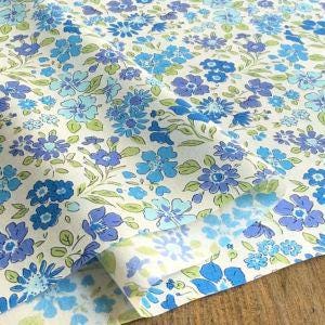 a close-up view of a fabric with a floral pattern in shades of blue and green. The fabric appears to be folded or creased, creating a textured appearance.