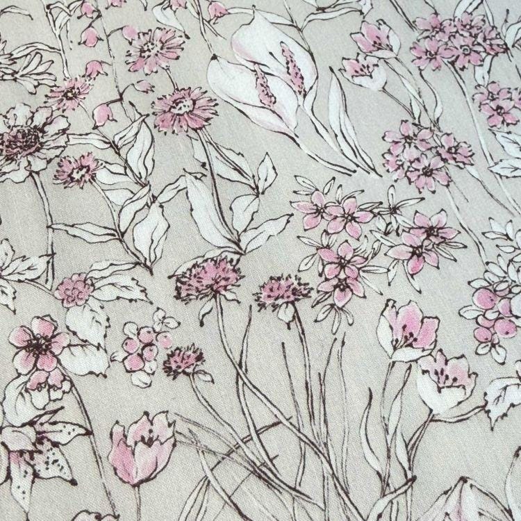 a close-up view of a fabric with a floral pattern. The pattern consists of various flowers and leaves in shades of pink and white, creating a visually appealing and intricate design.