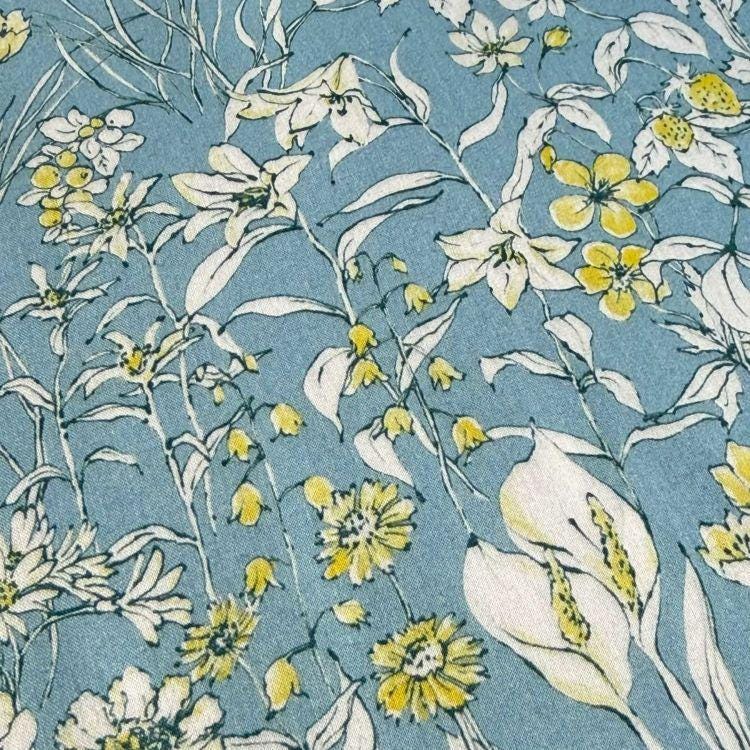 a close-up view of a fabric with a floral pattern. The fabric has a blue background with white flowers and leaves, creating a visually appealing and intricate design.