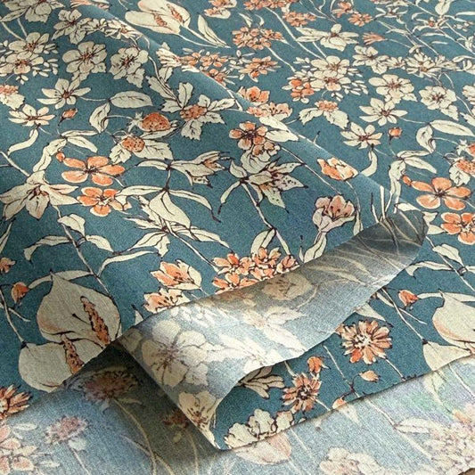 a close-up view of a fabric with a floral pattern in shades of blue and orange. The fabric appears to be folded or rolled, revealing the intricate design of the flowers and leaves.