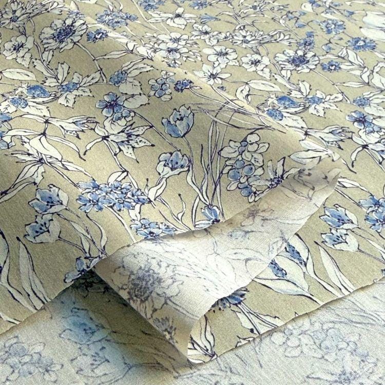 a close-up view of a fabric with a floral pattern in shades of blue and white. The fabric appears to be a piece of clothing or textile, with the intricate floral design visible on the surface.