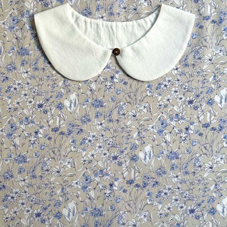 a white collar with a button, set against a background of a floral print fabric.