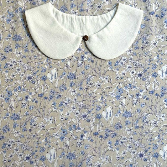 a white collar with a button, set against a background of a floral print fabric.
