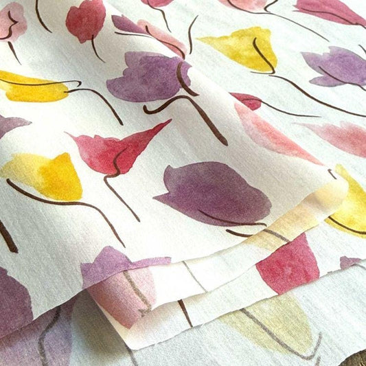 a close-up view of a fabric with a repeating pattern of colorful flowers, including yellow, pink, and purple flowers.