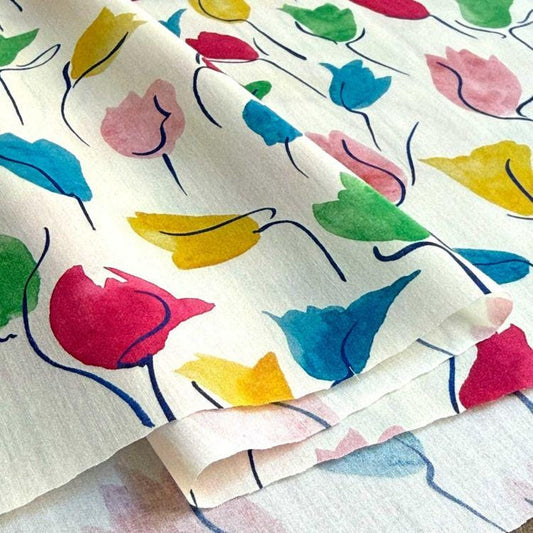 a close-up view of a fabric with a vibrant, colorful floral pattern. The pattern consists of various flowers in different colors, including red, yellow, green, and blue, creating a lively and eye-catching design.