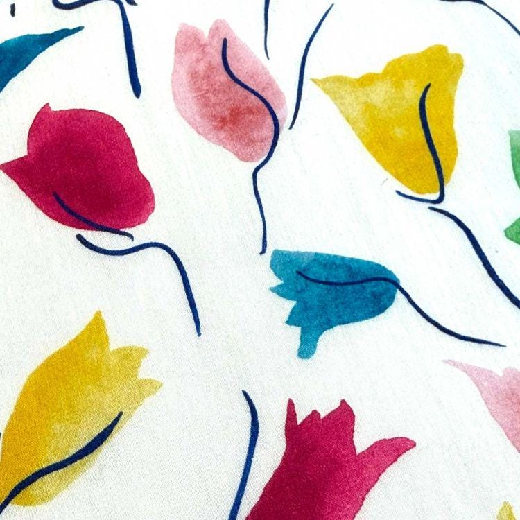 a close-up view of a white fabric with a vibrant and colorful floral pattern. The pattern consists of various flower shapes in different colors, including red, yellow, and blue, creating a visually striking and lively design.