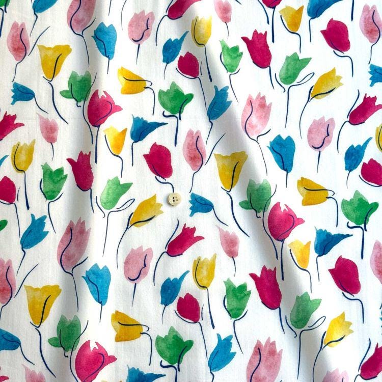 a close-up view of a fabric with a repeating pattern of colorful watercolor flowers in various shades of pink, yellow, green, and blue.