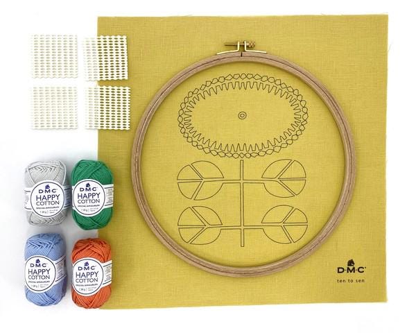 a sewing kit containing various supplies, including embroidery floss, a hoop, and a pattern for creating a flower design.