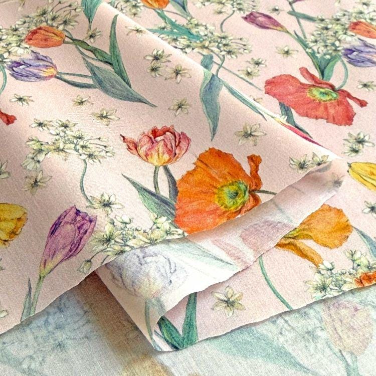 a close-up view of a fabric with a floral pattern, including various types of flowers such as tulips, poppies, and daisies. The flowers are depicted in different colors, creating a vibrant and visually appealing design.