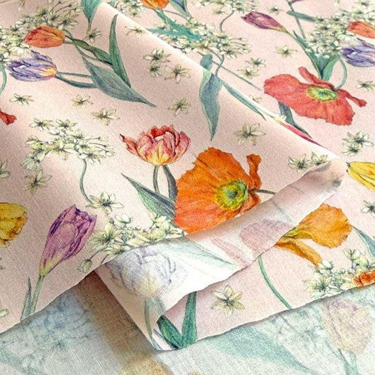 a close-up view of a fabric with a floral pattern, including various types of flowers such as tulips, poppies, and daisies. The flowers are depicted in different colors, creating a vibrant and visually appealing design.