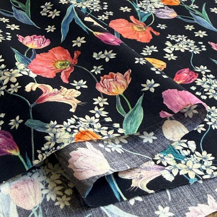a close-up view of a fabric with a floral pattern. The fabric has a black background with a variety of colorful flowers, including red, pink, orange, and white flowers, as well as green leaves. The flowers are arranged in a visually appealing manner, creating a vibrant and lively design.