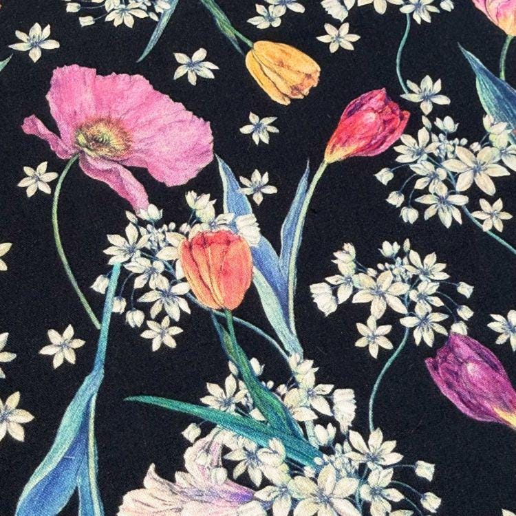 a close-up view of a black background adorned with a vibrant floral pattern. The pattern consists of various flowers, including tulips and poppies, as well as small white flowers. The flowers are arranged in a way that creates a visually appealing and intricate design, with the colors and shapes of the flowers standing out against the dark background.