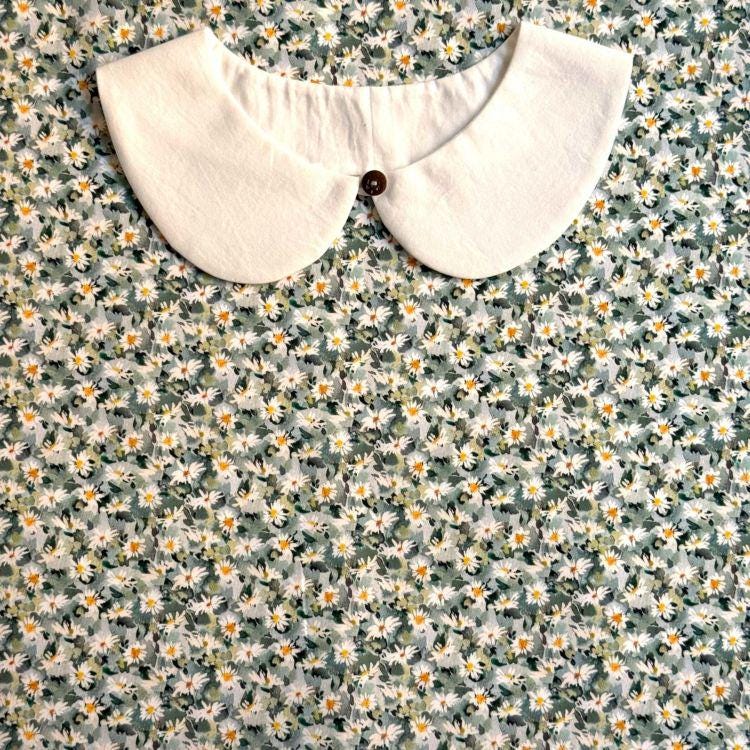 a white collar with a button, set against a background of a floral print fabric.