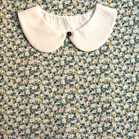 a white collar with a button, set against a background of a floral print fabric.