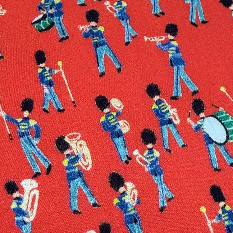 a vibrant red background with a repeating pattern of blue and yellow marching band members playing various instruments, such as drums, trumpets, and saxophones.