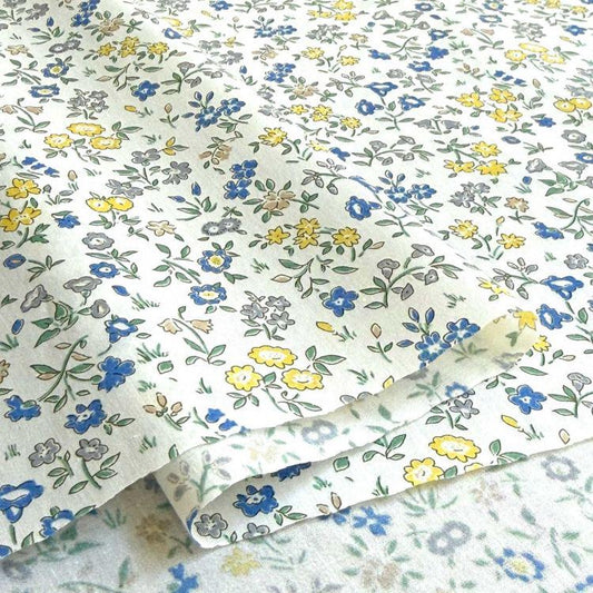a close-up view of a fabric with a floral pattern in shades of blue, yellow, and white. The fabric appears to be folded or rolled, revealing the intricate design of the flowers and leaves.
