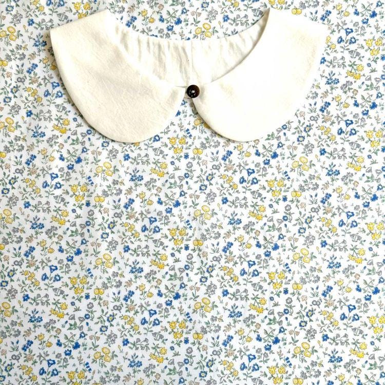 a white collar with a button, set against a background of a floral print fabric.