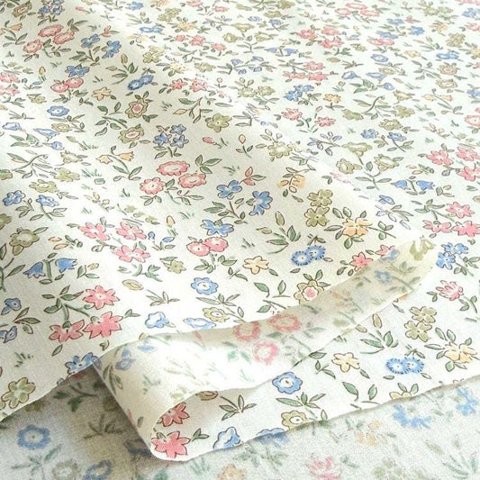 a close-up view of a fabric with a floral pattern, featuring various shades of pink, blue, and green flowers and leaves.