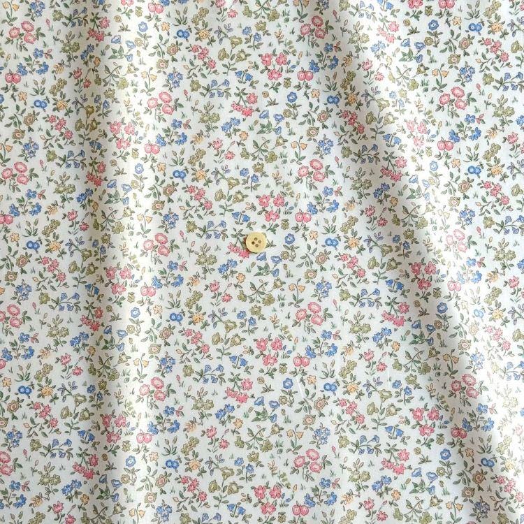 a close-up view of a fabric with a floral pattern, featuring a small yellow button in the center.