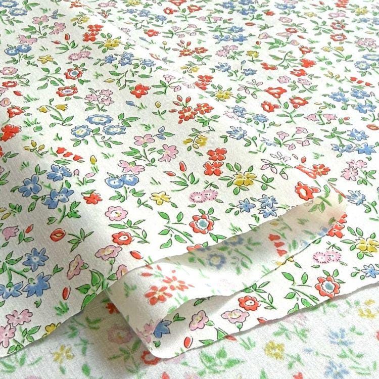 a close-up view of a fabric with a floral pattern, featuring various colors and shapes of flowers and leaves.