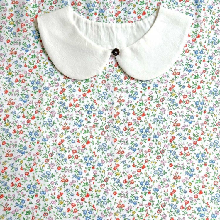 a white collar with a button, set against a background of a colorful floral print.