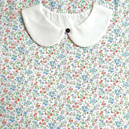 a white collar with a button, set against a background of a colorful floral print.