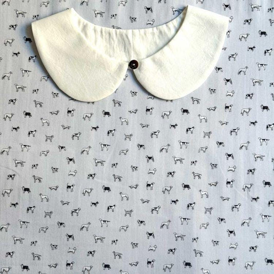 a white collar with a button, set against a background with a repeating pattern of black and white dog illustrations.