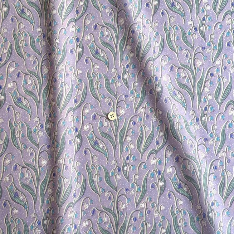a fabric with a repeating pattern of purple flowers and green leaves, creating a visually appealing and intricate design.