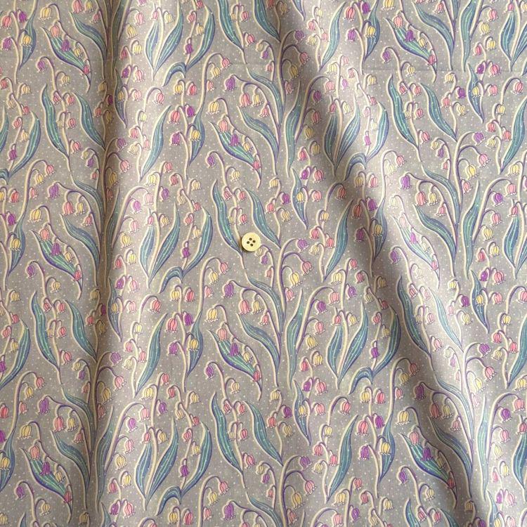a fabric with a repeating pattern of flowers and leaves in shades of pink, blue, and green. The pattern is intricate and detailed, creating a visually appealing design.