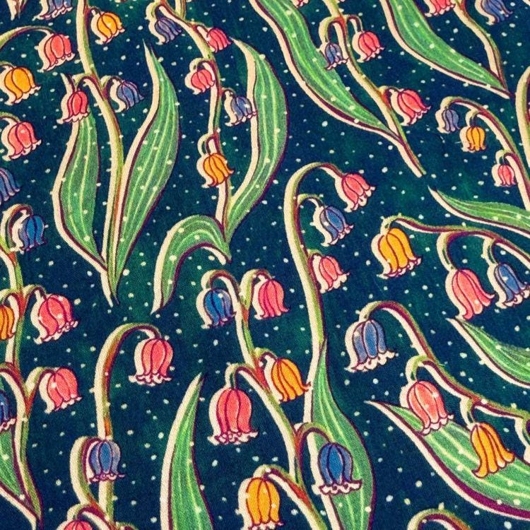 a close-up view of a patterned fabric with a repeating design of colorful flowers and leaves against a dark background.